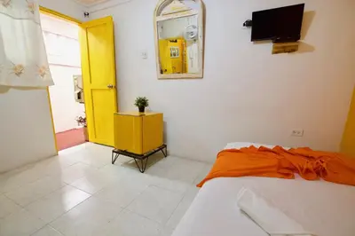 a bedroom with a bed and a yellow door at QuillaHost Guesthouse in Barranquilla