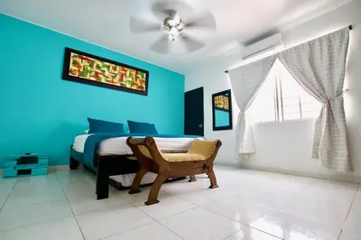a bedroom with blue walls and a bed with a chair at QuillaHost Guesthouse in Barranquilla