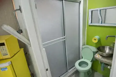 a small bathroom with a toilet and a shower at QuillaHost Guesthouse in Barranquilla