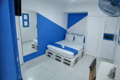 a blue and white bedroom with a bed and a mirror at QuillaHost Guesthouse in Barranquilla