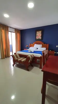 a bedroom with two beds and a blue wall at Hotel Dorado BAQ in Barranquilla