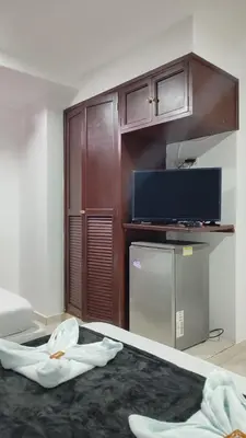 a room with a bed with a tv and a refrigerator at Hotel Dorado BAQ in Barranquilla