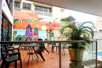 a balcony with tables and chairs and a mural at Hotel Dorado BAQ in Barranquilla