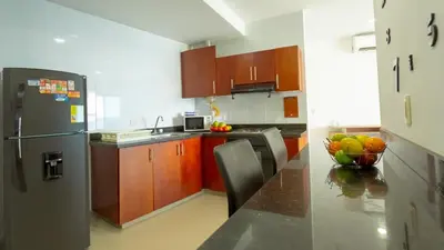 a kitchen with a refrigerator and a table with a bowl of fruit at Apartamento Vista Mar 1707 in Cartagena de Indias