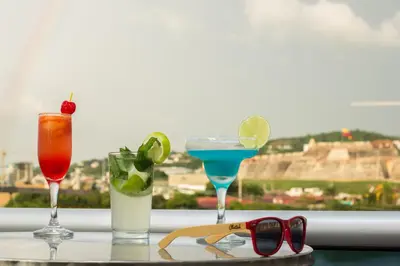 three cocktails on a table with a view of the coliseum at Voilá Signature Casa Isabel in Cartagena de Indias