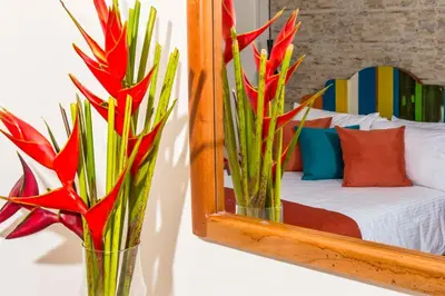 a mirror with two vases with flowers in front of a bed at Voilá Signature Casa Isabel in Cartagena de Indias