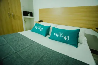 a bed with two blue pillows on top of it at Hotel Plaza 43 in Barranquilla