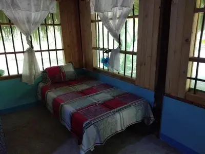 a bed sitting in a room with windows at Ecohotel Arte y Aventura in Isla Grande
