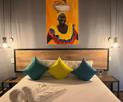 a bed with colorful pillows and a painting of a woman at Maloka Boutique Centro Histórico in Cartagena de Indias