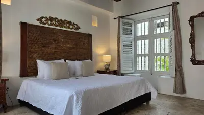 a bedroom with a white bed with a large window at Hotel Casa la Tablada in Cartagena de Indias