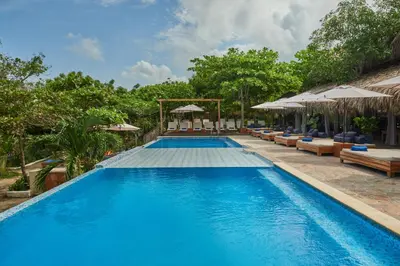 a large swimming pool with chairs and umbrellas at Blue Apple Beach in Tierra Bomba