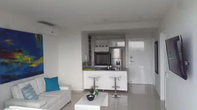 a white living room with a couch and a kitchen at Apartamento Morros Epic Cartagena in Cartagena de Indias