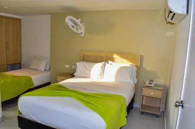 a hotel room with two beds with green sheets at Hotel Isla Capri in Cartagena de Indias