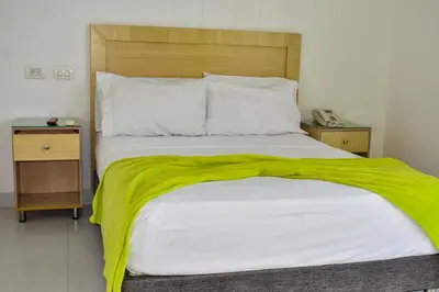 a bedroom with a bed with a green blanket on it at Hotel Isla Capri in Cartagena de Indias