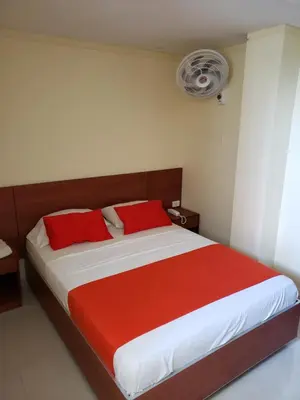 a bedroom with a bed with red pillows and a fan at Hotel Sandiego inc in Barranquilla
