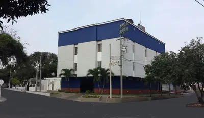 a white and blue building with palm trees in front of it at Hotel Sandiego inc in Barranquilla