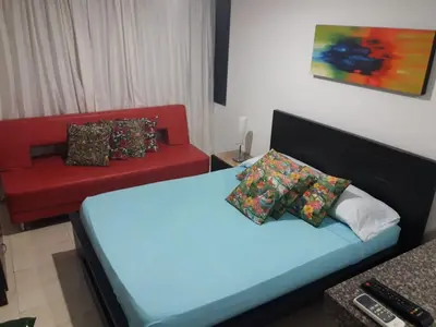 a bedroom with a bed and a red couch at Apartamento Playero in Cartagena de Indias