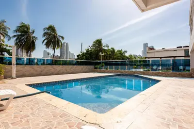 a swimming pool with blue water and palm trees at BW Apartments in Cartagena de Indias