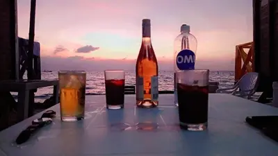 a table with two bottles and glasses on the beach at Pura Vida Baru - La Casa del Cholo in Baru
