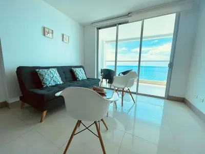 a living room with a couch and chairs and the ocean at Apartamento Frenta a la Playa in Cartagena de Indias