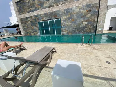 a person laying on a chair next to a swimming pool at Apartamento Frenta a la Playa in Cartagena de Indias