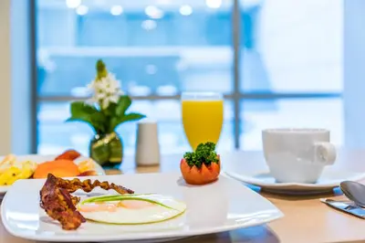 a table with a plate of food and a glass of orange juice at Ribai Hotels - Barranquilla in Barranquilla