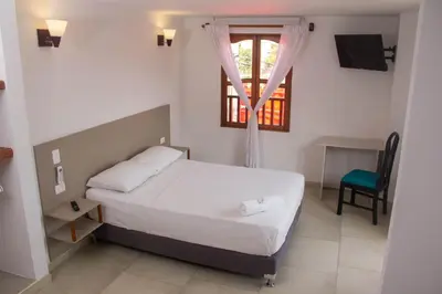 a bedroom with a bed and a window and a chair at Akel House Hotel in Cartagena de Indias