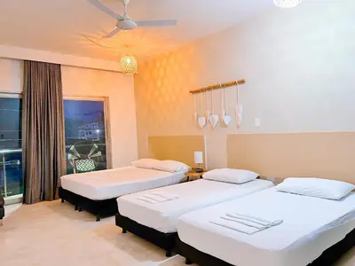 a room with three beds and a window at Awa De Mar Hotel Tolu in Tolú