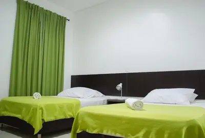 two beds in a room with green curtains at Hotel Las Olas Mamonal in Cartagena de Indias