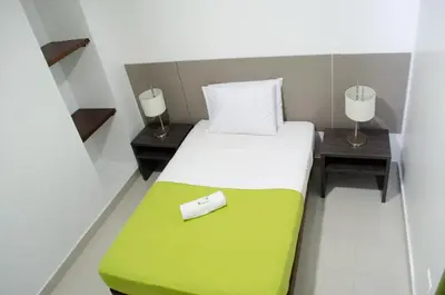 a bedroom with a bed with a green and white blanket at Hotel las Olas Malambo in Malambo