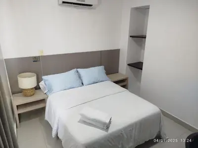 a bedroom with a white bed with blue pillows at Hotel las Olas Malambo in Malambo