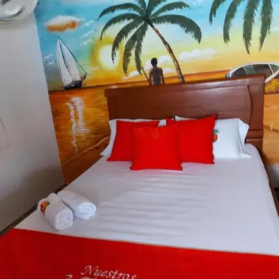 a bed with red pillows and a painting on the wall at Nuestros Tres Tesoros II in Playa Blanca