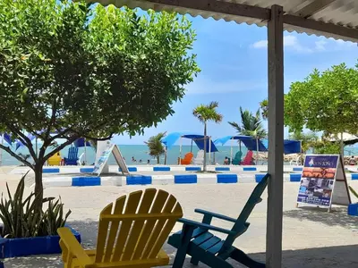 two chairs sitting on a beach with the ocean in the background at Hotel Don Toño Tolú in Tolú