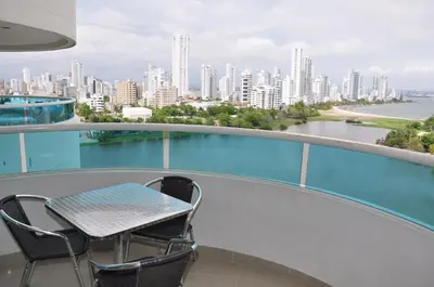 a table and chairs on a balcony with a view of a city at Torres del Lago Apartamentos in Cartagena de Indias