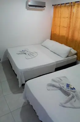 two beds in a room with white sheets at Hotel Torres del Parque No3 in Barranquilla