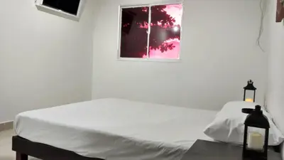 a white bedroom with a bed and a window at Hotel El Emigrante in Puerto Colombia