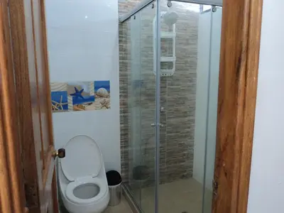 a bathroom with a toilet and a glass shower at Edificio Mar de Leva in Santa Marta