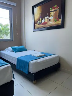 two beds in a room with a painting on the wall at Cabanas Villa Antonella Covenas in Coveñas