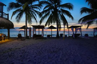 a beach with palm trees and the ocean at sunset at Hotel Camino Verde in Tolú