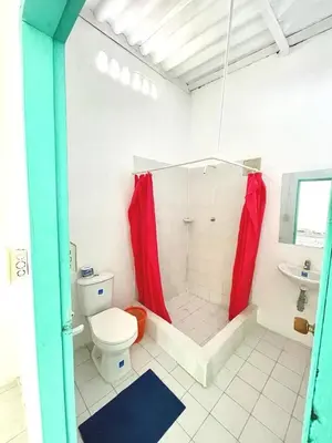 a bathroom with a toilet and a shower with red curtains at Costa de Vikingos in Tolú
