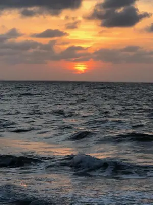 a sunset over the ocean with the sun setting at Costa de Vikingos in Tolú
