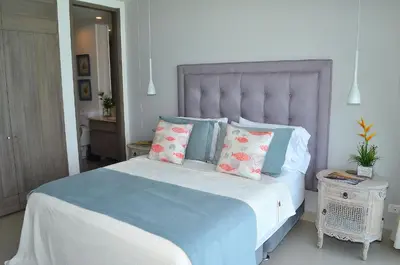 a bedroom with a large bed with blue and pink pillows at Namaste Alojamientos Luxury Cartagena in Cartagena de Indias