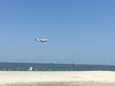 an airplane is flying over the beach with a boat at Costa Azul Suite 606 in Santa Marta