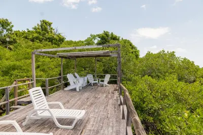 a wooden deck with white chairs and trees at Hotel Playa Scondida Barú in Baru