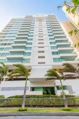 a large white building with palm trees in front of it at Travelers Orange Cartagena in Cartagena de Indias