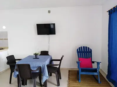 a dining room with blue chairs and a table with a red pillow at Cabañas Cigua in Coveñas