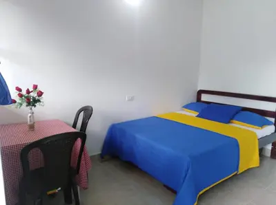 a bedroom with a blue and yellow bed and a table at Cabañas Cigua in Coveñas