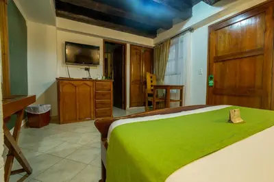 a bedroom with a large bed with a green blanket at Hotel Don Pedro De Heredia in Cartagena de Indias