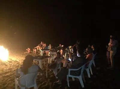 a group of people sitting around a fire on the beach at Gran Muelle Hotel in San Bernardo del Viento