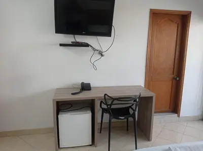 a desk with a chair and a television on a wall at Hotel Damys in Sincelejo